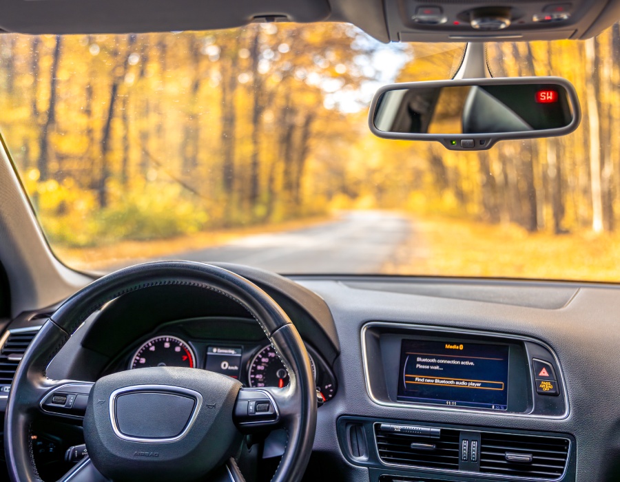 Pare-brise propre et dégagé pour une conduite sûre en automne Vue intérieure d’une voiture sur route forestière à travers un pare-brise propre et dégagé en automne.